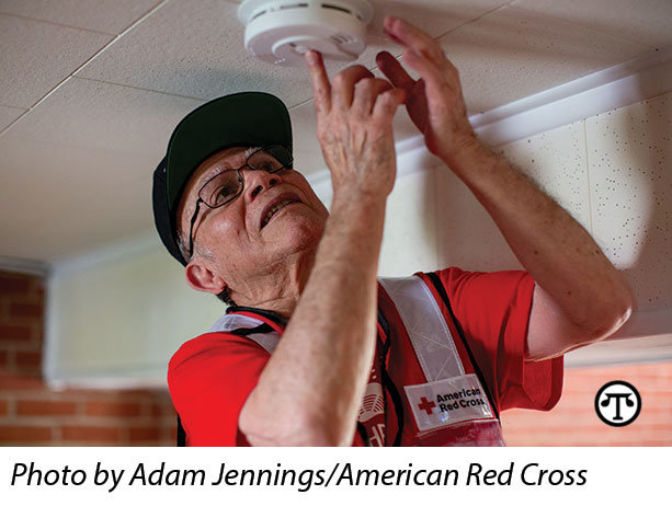A Red Cross volunteer installs a free smoke alarm    through the Home Fire Campaign.